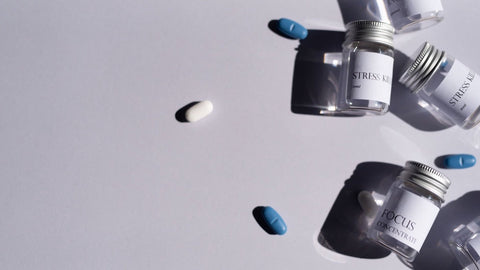 Flacons de compléments alimentaires pour le stress étiquetés stress et focus, entourés de gélules bleues et blanches
